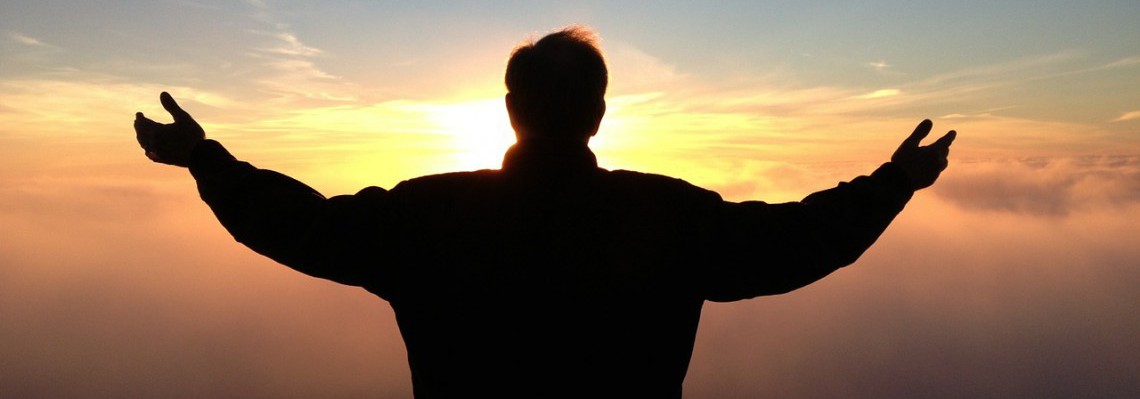 Man praying silhouetted against evening sunset