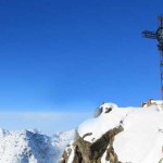 Christian cross on snow covered mountain peak.